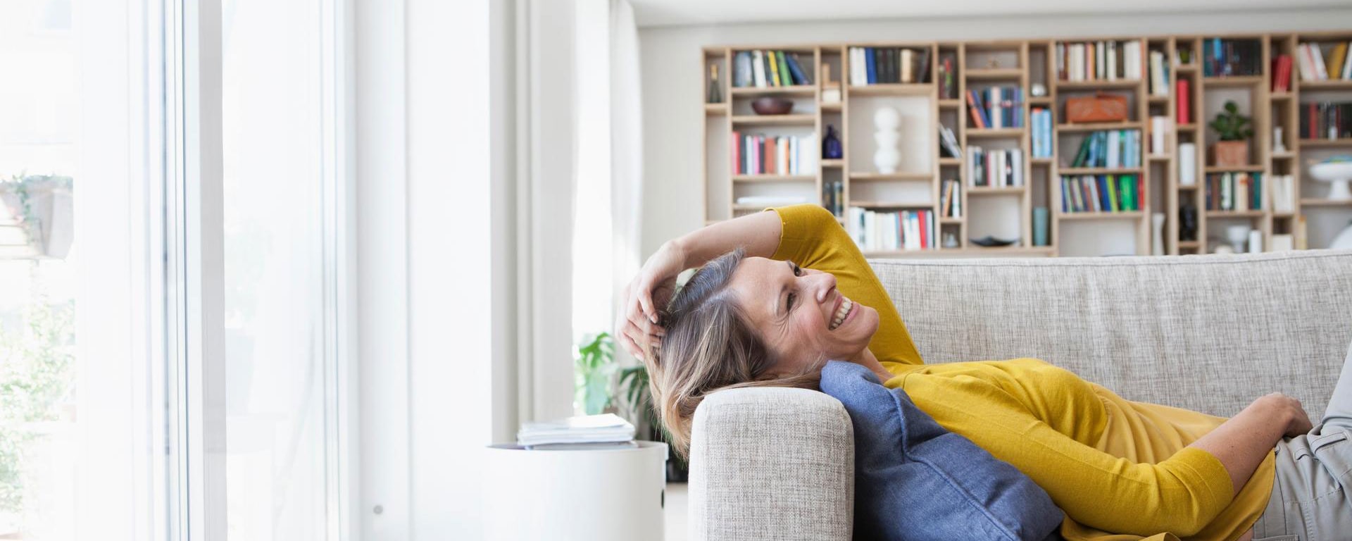 A woman is lying on the sofa, laughing.