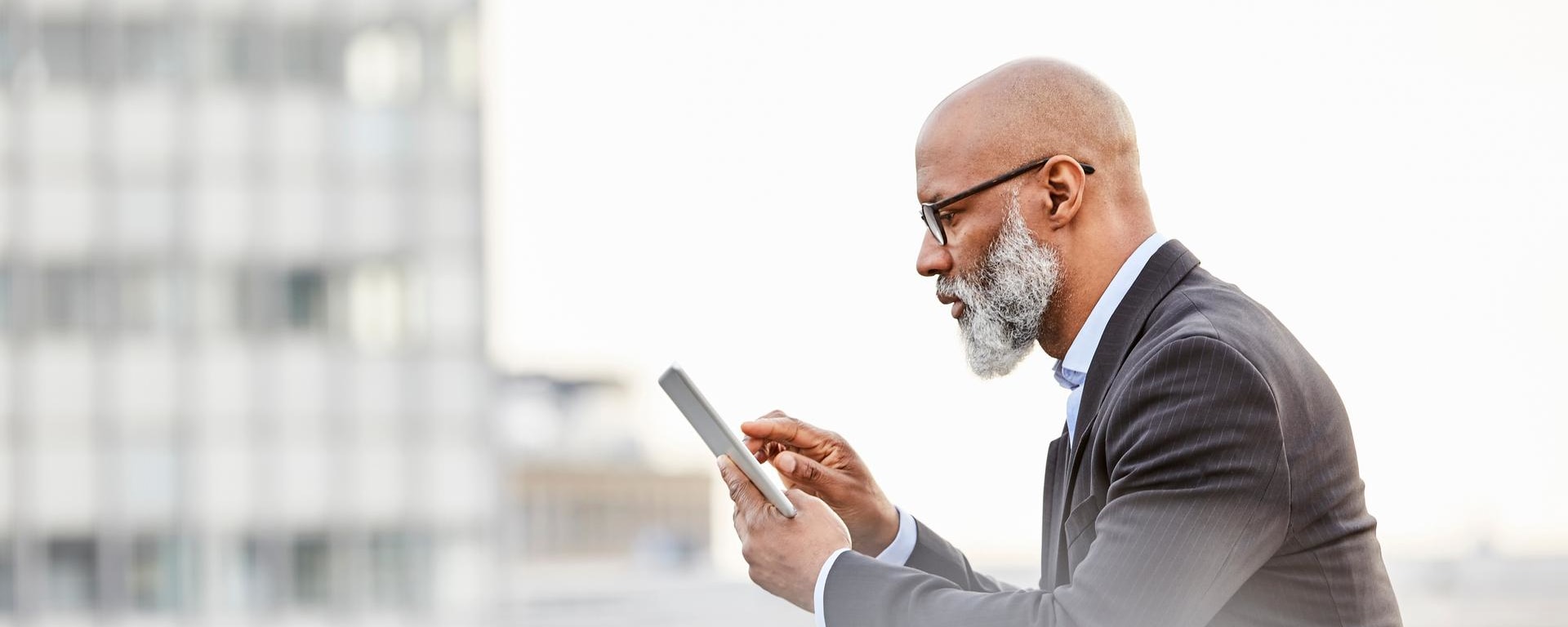 A man stands at a railing, looking at his smartphone.