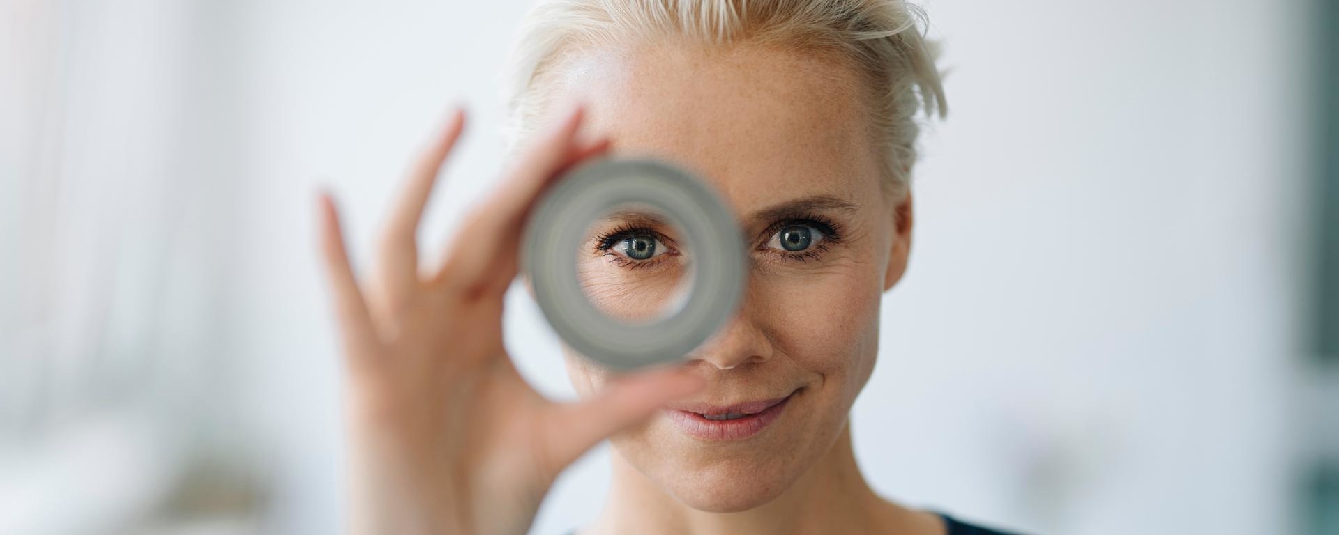 A woman looks attentively through a tube.