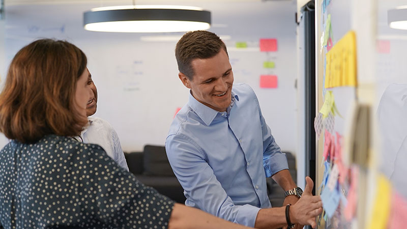 A man and a woman stand in front of a whiteboard and discuss a presentation, symbolize professionals.