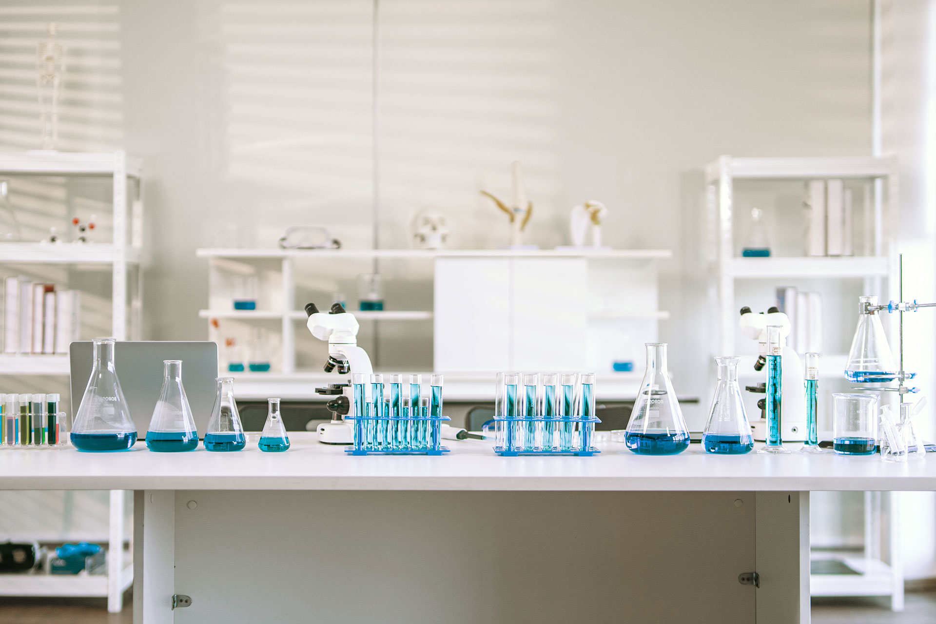 Photo of a laboratory with a desk in the center and several bottles containing blue liquid placed on it.